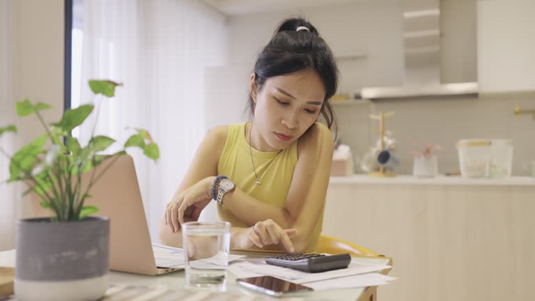Upset woman thinking about high prices while looking at utilities, gas, electricity, rental charges, Planning personal budget while sitting in kitchen