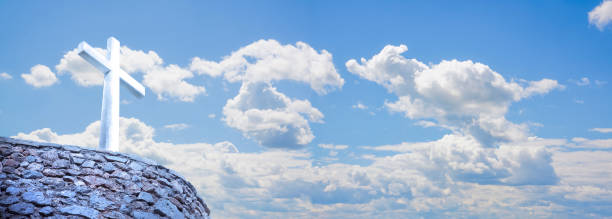 Stone christian cross against a cloudy sky - concept image with copy space.