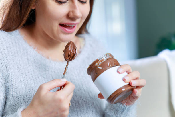 istock Young woman eating chocolate from a jar at home 1935126343