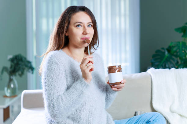 istock Young woman eating chocolate from a jar at home 1935126891