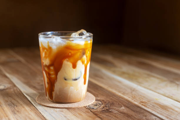 ice caramel macchiato coffee on wooden table. - caffè macchiato stockfoto's en -beelden