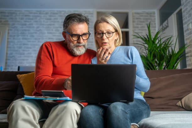 istock Serious couple sitting on couch in new home checking bills 1935152873