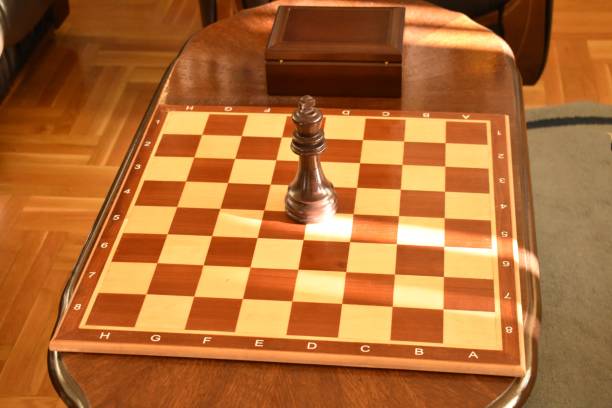 a sunlit room containing a table with a chessboard containing a queen and a piece box