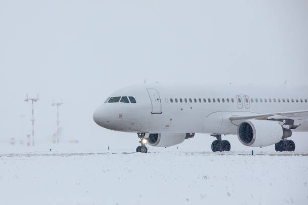 Traffic at airport during snowfall. Passenger airplane taxiing to runway for take off on frosty winter day.