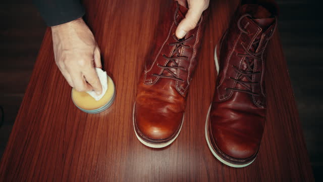 Man waxing, rubbing, shining, brushing and polishing leather boot shoes