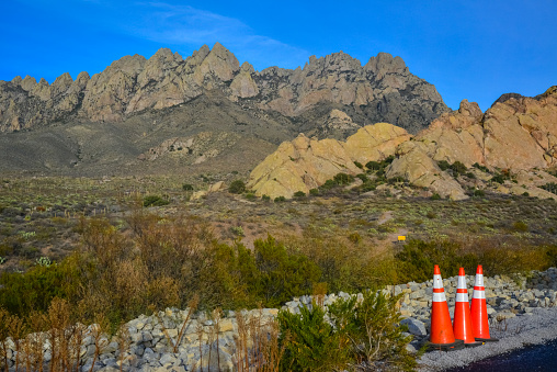 Red road warning signs near a road in the background of mountains in New Mexico, USA