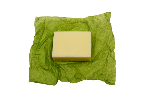 bar of soap on green paper wrapper on white background
