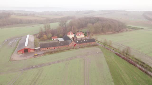 Aerial View Of Farm Buildings And Fields On A Misty Morning.
