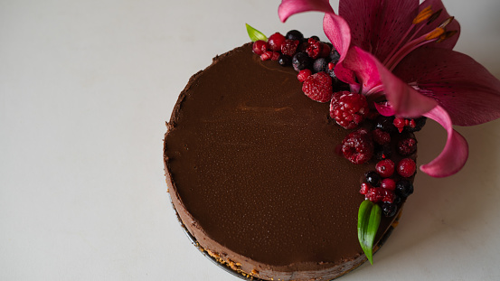 chocolate cake with red berrys and a big flower on a white background