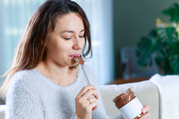 istock Young woman eating chocolate from a jar at home 1935190937