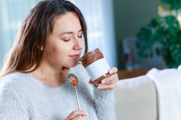 istock Young woman eating chocolate from a jar at home 1935191473