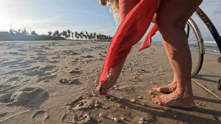 Mature woman pushes bike along empty beach