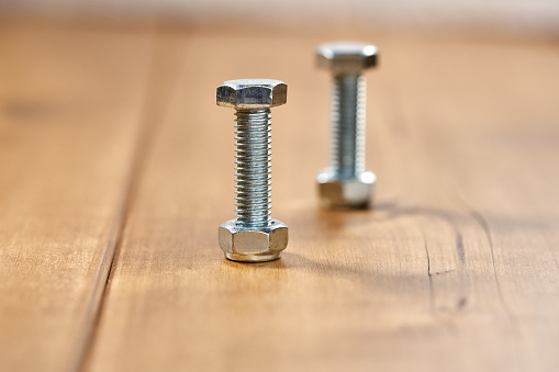 Two thread screws on a wooden table.