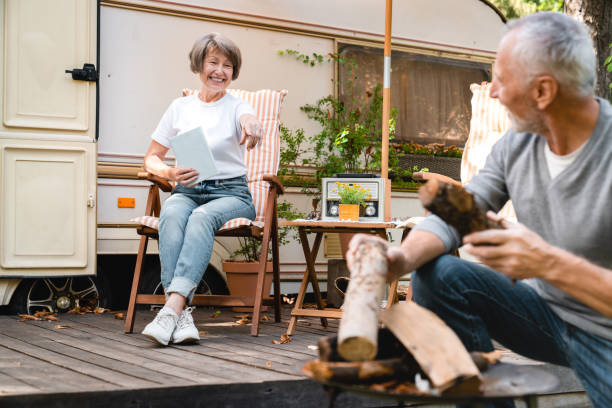 istock Senior old elderly husband laying a fire with firewood communicating with wife 1935243813
