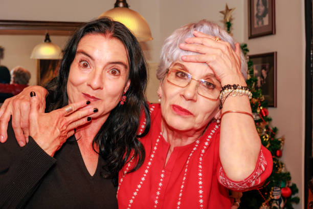 Two Colombian ladies, an older lady with her niece, looking directly into the camera appear to be very surprised.  It is party time for the senior lady!