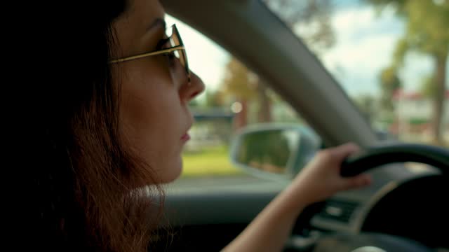 Portrait confident brunette in stylish sunglasses driving car at sunset