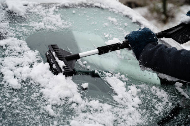 istock Driver is removing snow from car windshield with ice scraper and broom, clean car window from icy frost, winter season 1935262783