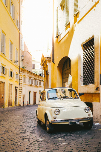 Small vintage car on a street in Rome on a sunny summer day with no people