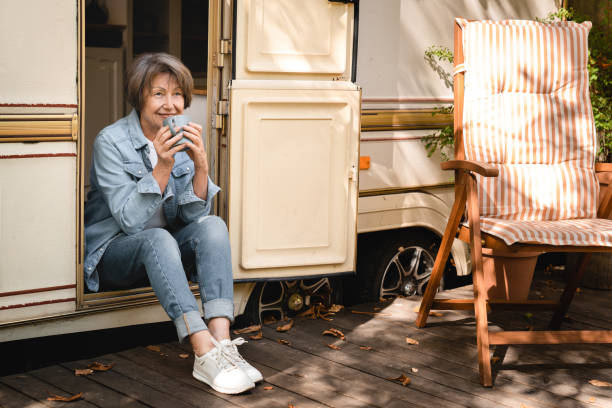 grand-mère pleine longueur buvant du café reposant sur le porche de la remorque - motor home mobile home camping senior adult photos et images de collection