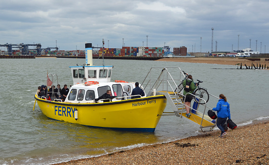 Felixstowe, Suffolk, England- May 28, 2021:  Harwich to Felixstowe and Shotley ferry takes up to twelve people and bicycles across the busy estuary, port of Felixstowe in background.