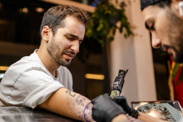 istock Young tattoo artist tattooing his customer in his studio 1935288815