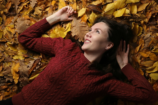 Young woman lies on yellow autumn foliage