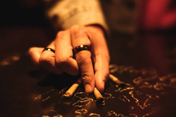 istock Detail of a man's hands lighting a marijuana cigarette under a red light. 1935331409