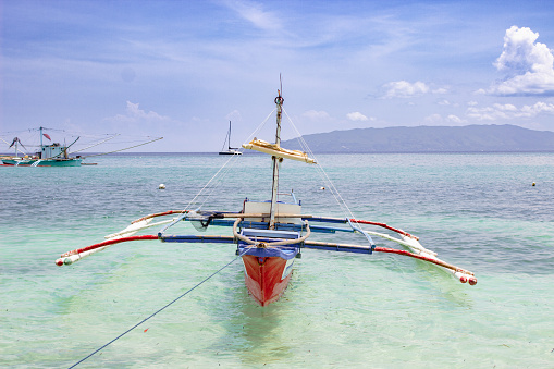Boat stranded on a paradise beach, attached to a rope, in Palawan, Philippines.