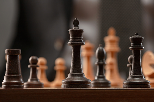 Chess pieces on the chessboard. Focus on the front figures. Shallow depth of field