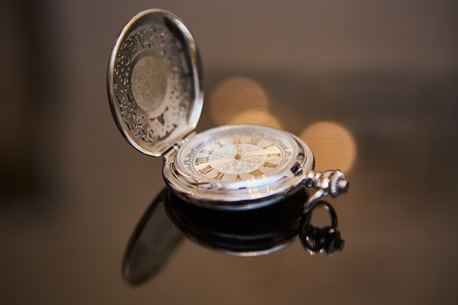 Vintage mechanical pocket watch in gold or brass color made of metal. Dial with Roman numerals with two hands.