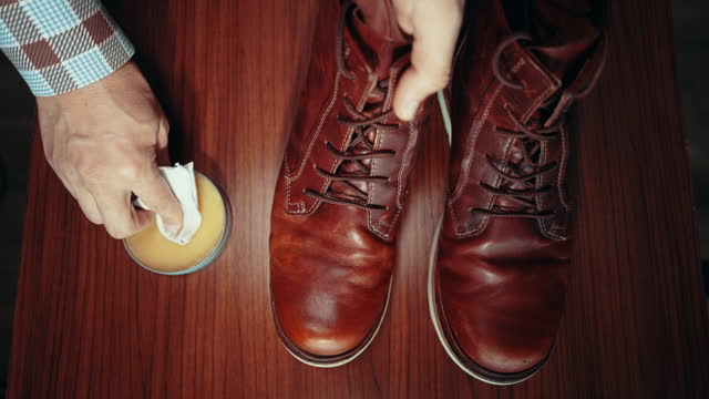 Man waxing, rubbing, shining, brushing and polishing leather boot shoes