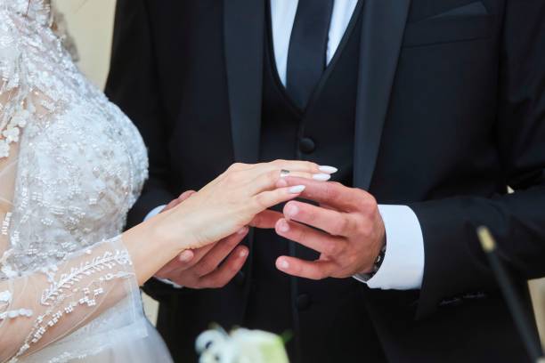 istock Wedding ring exchange ceremony at the wedding. The groom puts a ring on the bride 1935365167