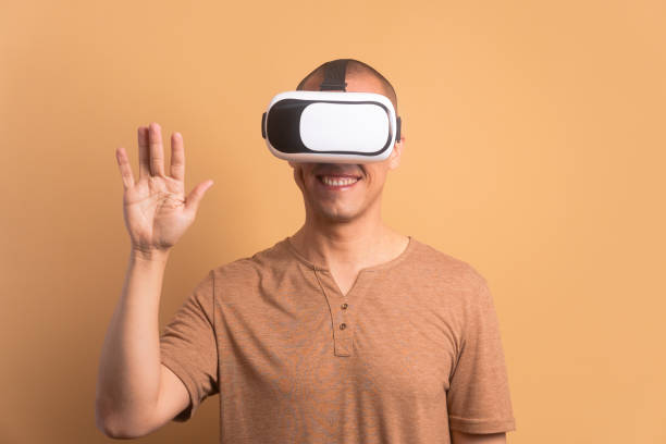 istock joyful brazilian man Using VR headset and gesturing in beige colors. virtual reality, technology simulation concept. 1935370931