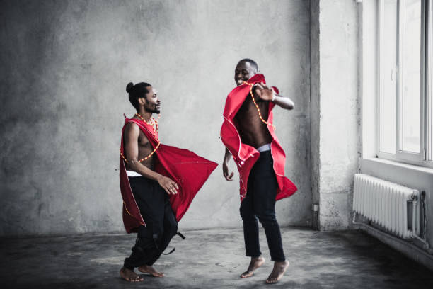 Two black young men in traditional costumes dancing in an empty room