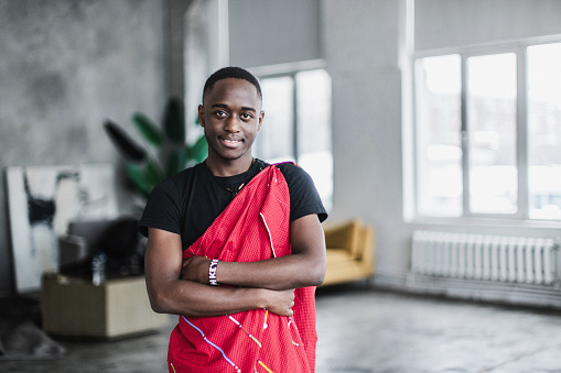 Portrait of beautiful African young man in traditional costume standing in a living room