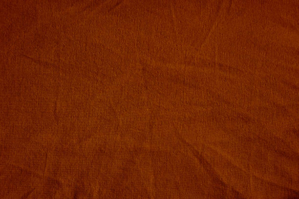 Dark deep burnt orange red brown terracotta texture background for design. Wrinkled crumpled natural cotton fabric cloth. Color.