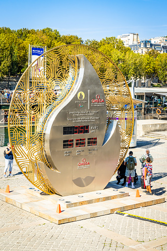 Paris, France - September 09, 2023 : Omega clock showing the days before the start of the Paris Olympics 2024 with tourists taking photos and visiting