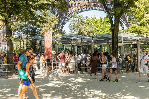 Paris, France - September 09, 2023 : Tourists standing in line at security gates at the entrance to the Eiffel Tower on a sunny day of summer