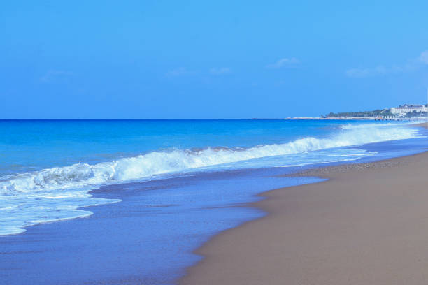 Seascape. Sandy beach sea shore with blue wave and white foam. Sea ​​waves on the sand on the beach. Blue sea waves on the beach for background. Abstract beach sand and soft wave background
