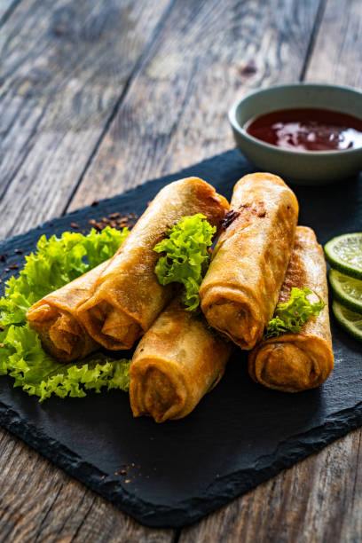 istock Spring rolls filled with meat and vegetables served with soy sauce on wooden table 1935420846