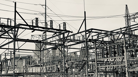 Monochrome image of cranes working on the construction site with a telecommunication tower in the backdrop