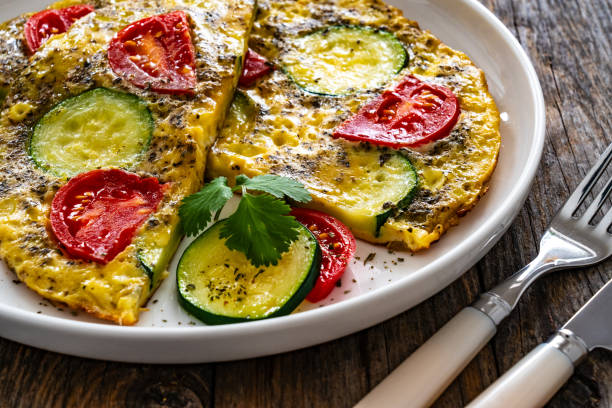 istock Omelet - scrambled eggs with cheese, zucchini and tomatoes on wooden table 1935431792