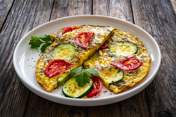 istock Omelet - scrambled eggs with cheese, zucchini and tomatoes on wooden table 1935432817