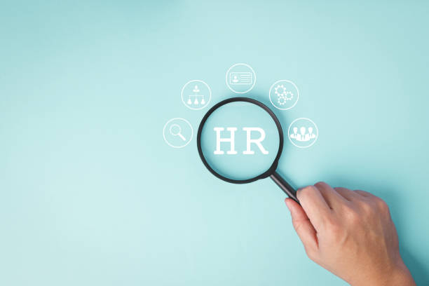 istock Hand holding magnifying glass to focused on HR text. 1935443964