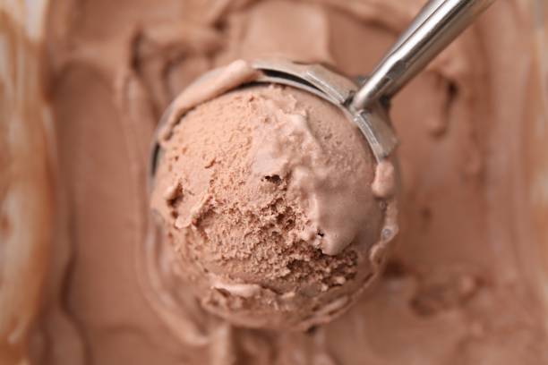 istock Taking tasty chocolate ice cream with scoop as background, closeup 1935456493