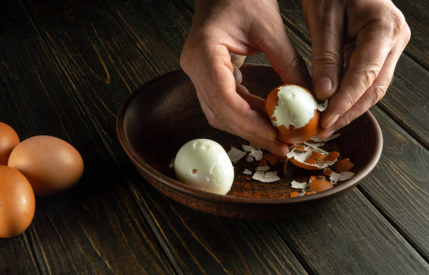 istock Cooking a delicious lunch with boiled eggs on the kitchen table. Shelling an egg with the hands of a cook. Advertising space. 1935463480