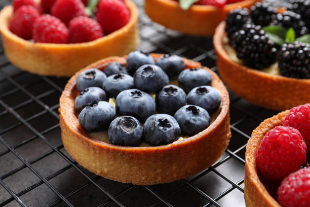 istock Tartlets with different fresh berries on cooling rack, closeup. Delicious dessert 1935466647