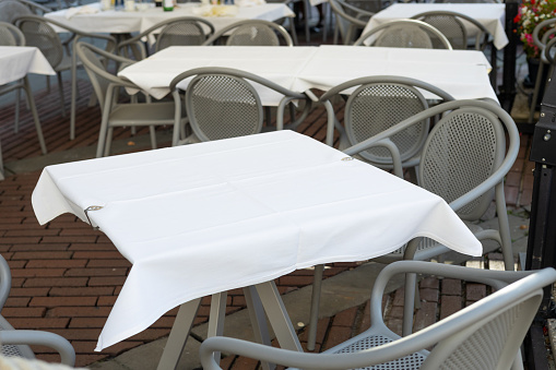 Dining outdoors. Outdoor street cafe tables ready for service. Empty cafe terrace with table and chair