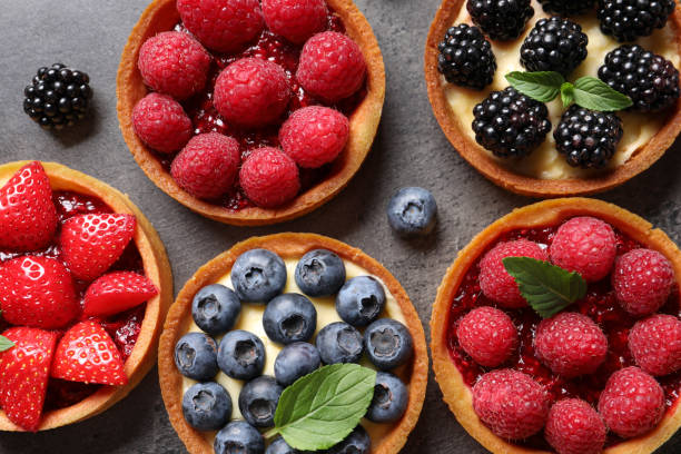 istock Tartlets with different fresh berries on grey table, flat lay. Delicious dessert 1935467694