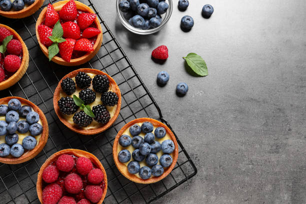 istock Tartlets with different fresh berries on grey table, flat lay and space for text. Delicious dessert 1935467696